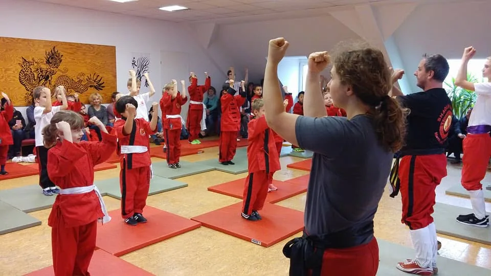 Kinder und Trainer üben gemeinsam eine Haltung im Redboat-Trainingsraum