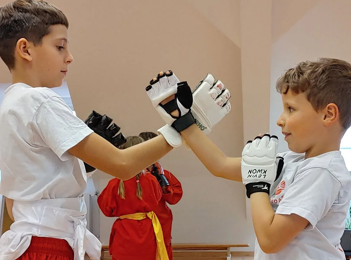 Zwei Kinder üben kontrolliert mit gepolsterten Handschuhen