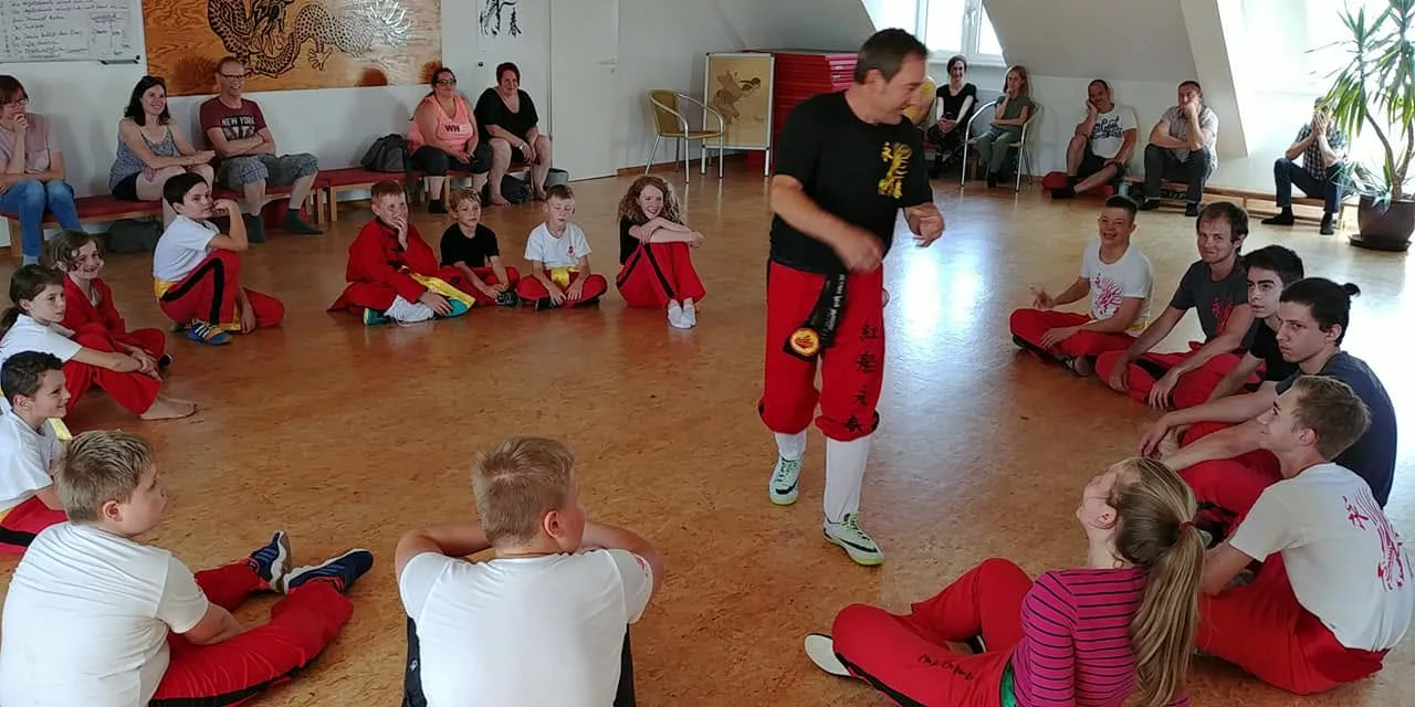 Kinder sitzen im Kreis und beobachten eine Übung